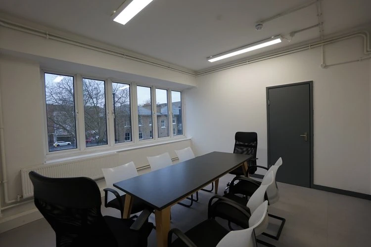 Meeting room with a dark table, office chairs and large windows.