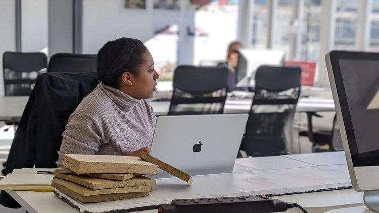 A person working on a laptop at a shared desk.