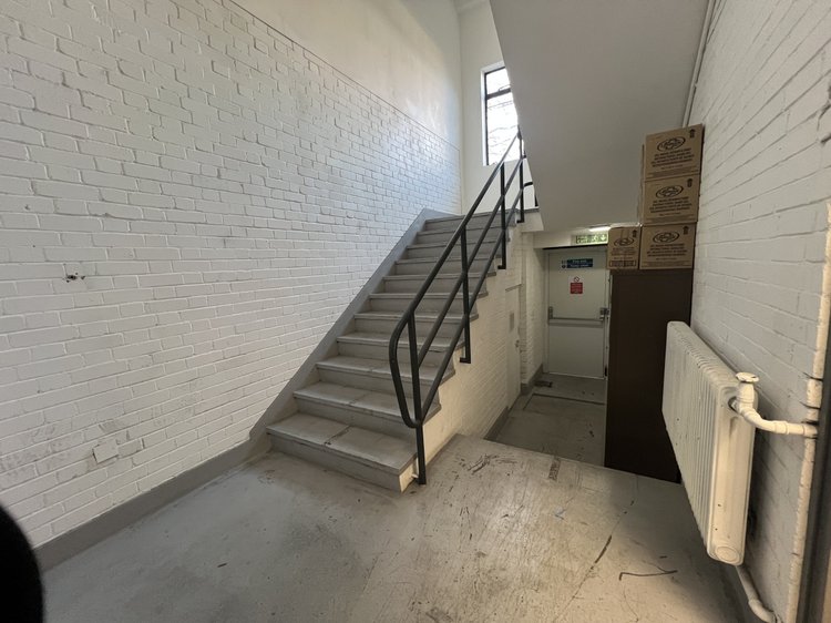 Concrete stairwell with white brick walls and metal handrails.