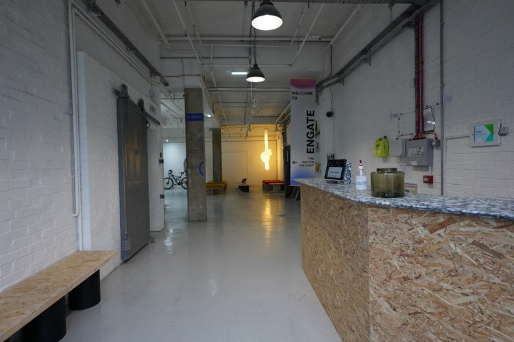 Ground-floor reception desk with an industrial corridor and seating beyond.