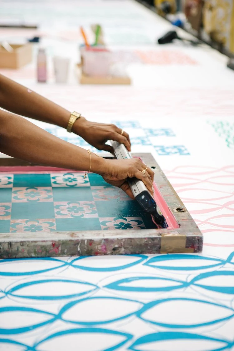Hands drawing a squeegee across a patterned screen.