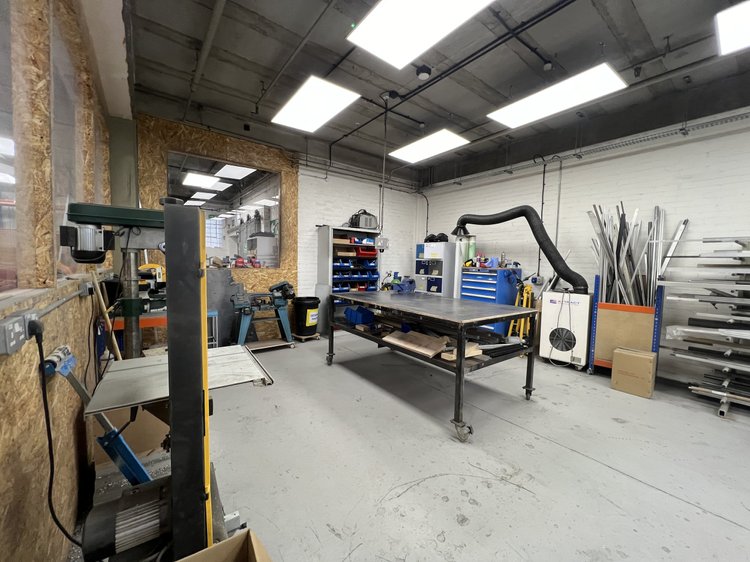 Metalworking bench with extraction equipment and metal stock storage.
